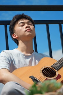 a man sitting on a balcony playing a guitar