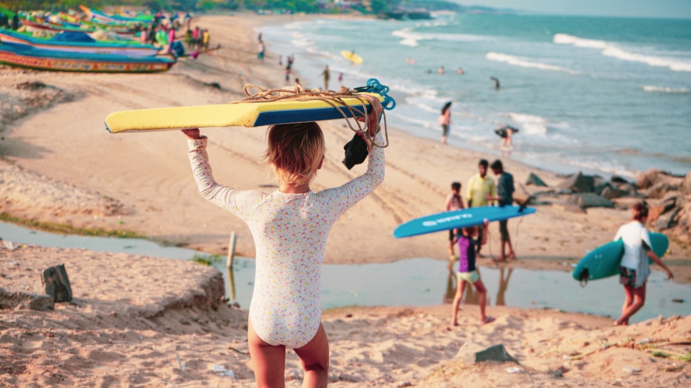 woman in white long sleeve shirt holding brown surfboard on beach during daytime