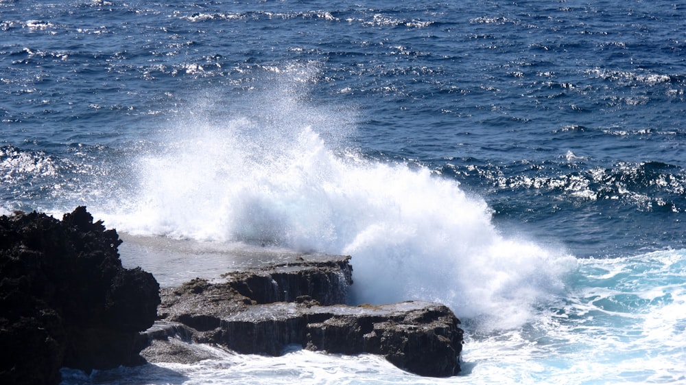 ocean waves crashing on rock formation during daytime