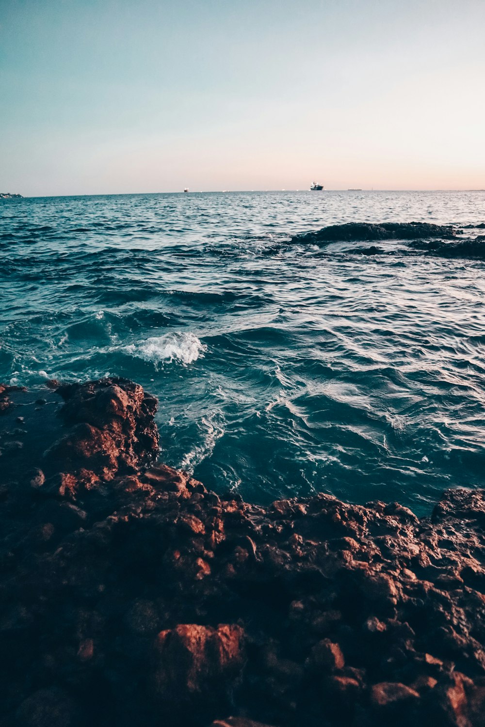 Les vagues de l’océan s’écrasent sur les roches brunes pendant la journée