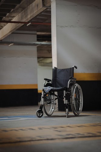 A wheelchair user rolling along a city sidewalk near a curb cut, passing storefronts