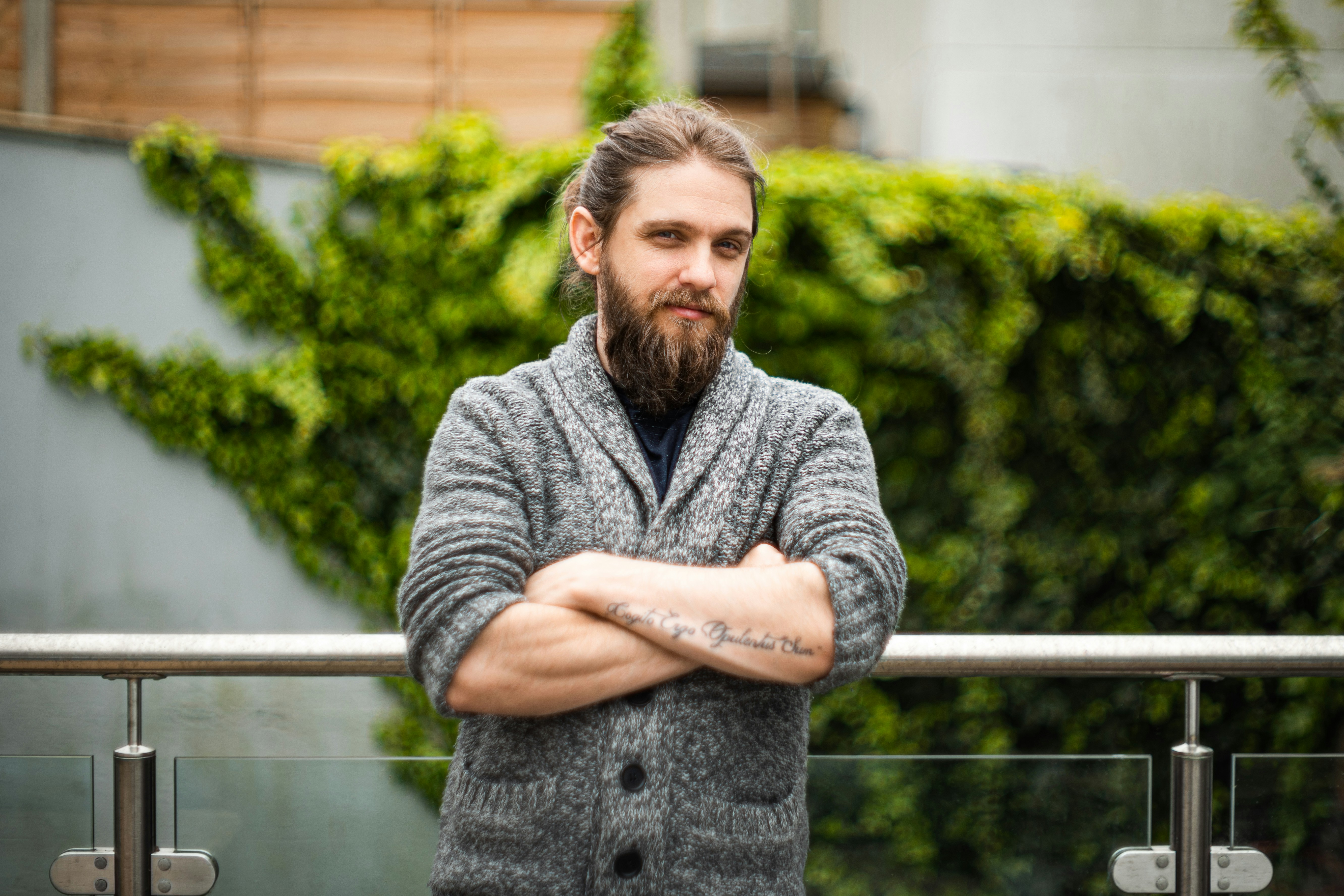 man in gray sweater standing near green plants during daytime