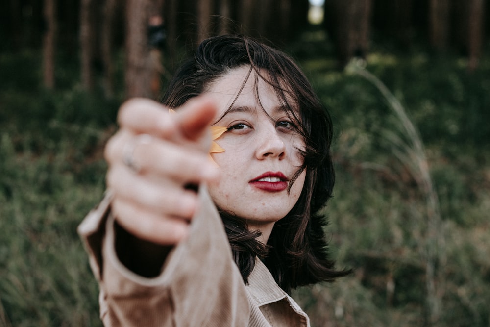 Femme en veste marron tenant une feuille jaune