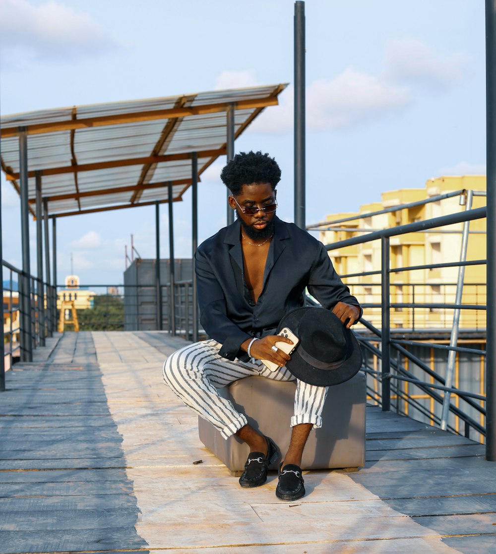 man in black jacket and black pants sitting on gray wooden bench during daytime