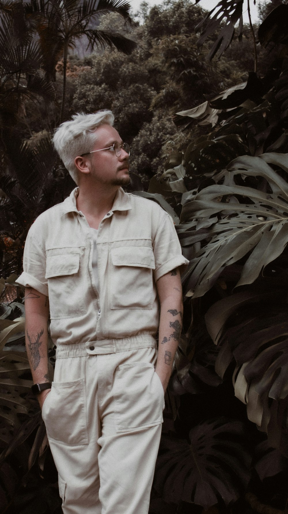 man in brown button up shirt standing near green plant