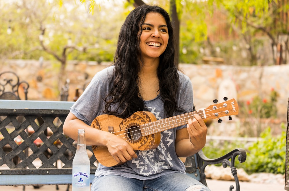 woman in gray long sleeve shirt playing acoustic guitar