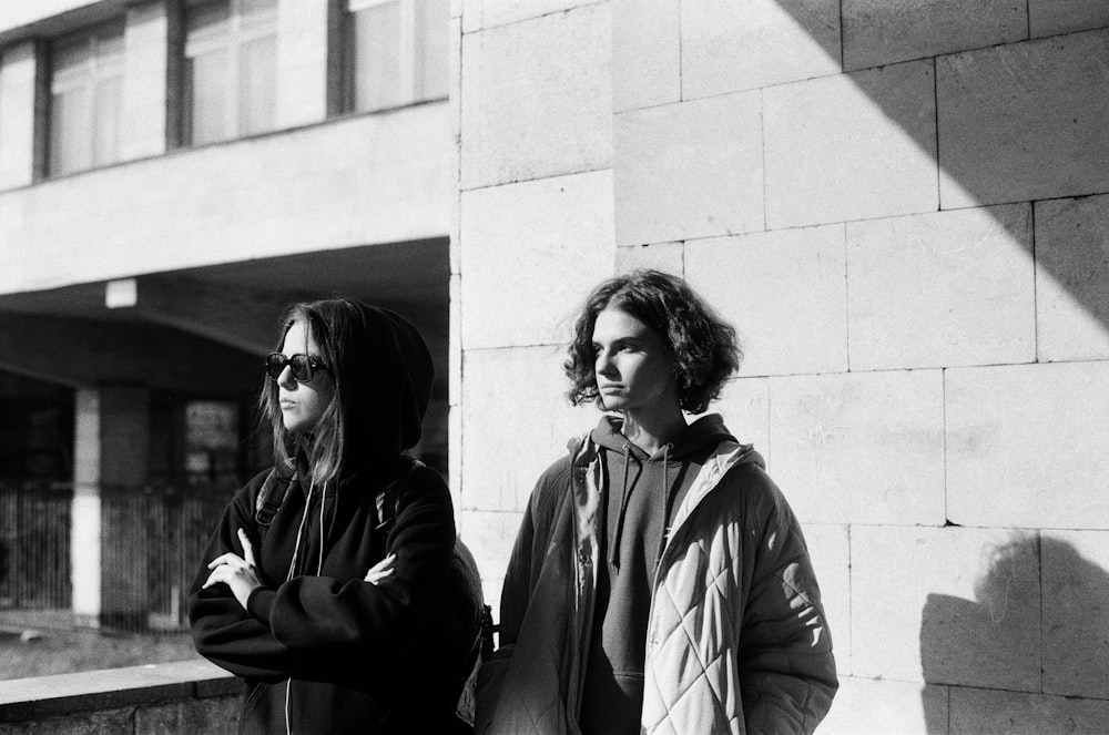 grayscale photo of woman in jacket standing beside woman in jacket