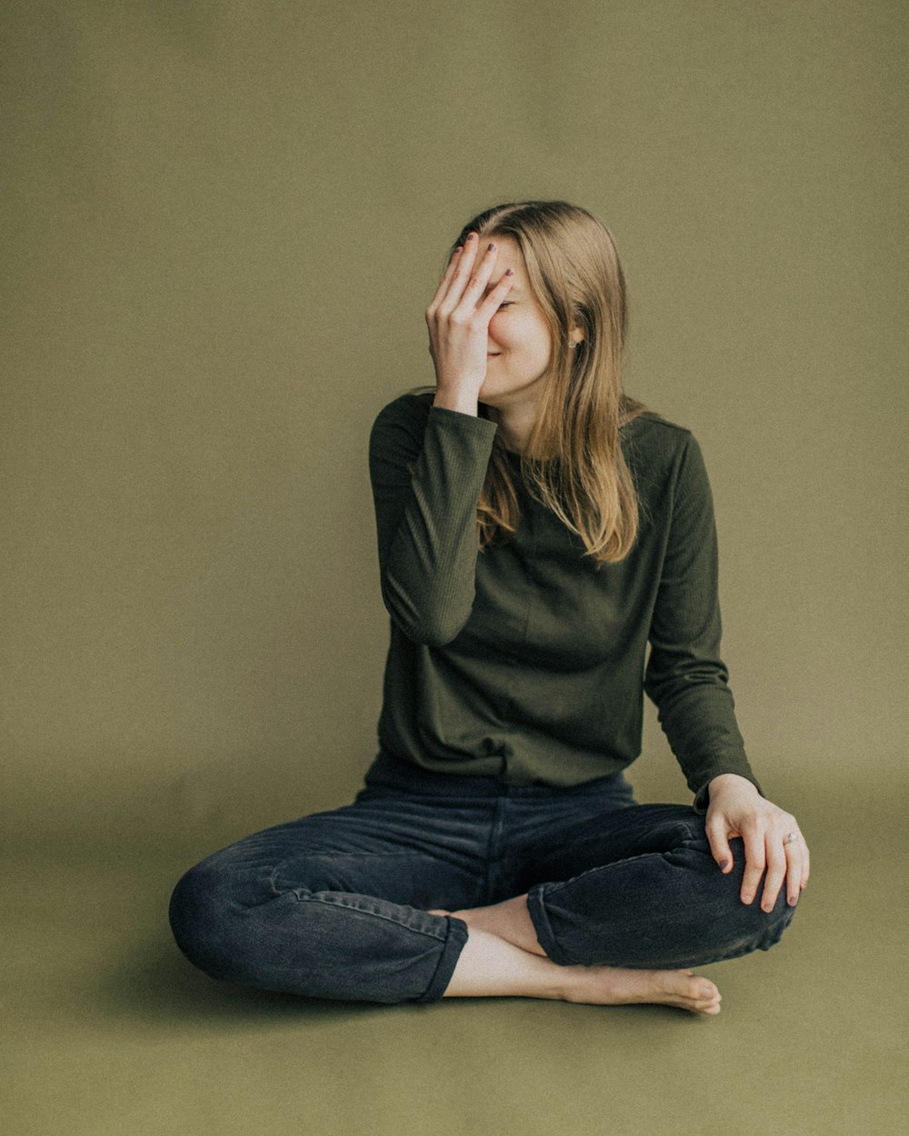 woman in black long sleeve shirt and blue denim jeans sitting on brown wooden chair