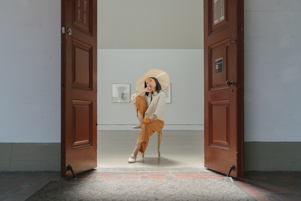 Femme en chemise blanche à manches longues et jupe marron debout à côté d’une porte en bois marron