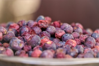 Close-up of vibrant, drum-dried organic berry powders in wooden bowls on a rustic table.