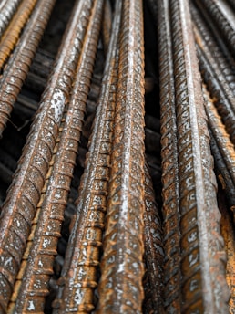 Close-up view of several rusty steel rebar rods stacked together, showing textured surfaces and signs of weathering.