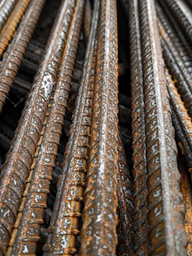 Close-up of neatly stacked mild steel wire rods cut to size with a dark industrial background.