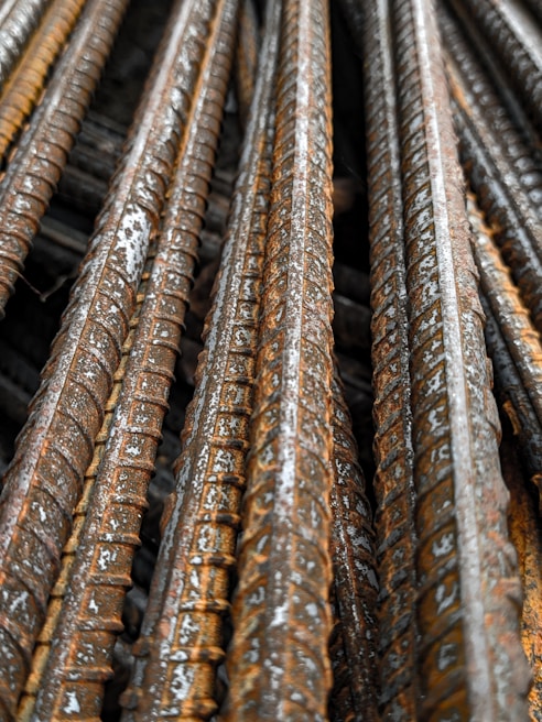 Close-up view of several rusty steel rebar rods stacked together, showing textured surfaces and signs of weathering.