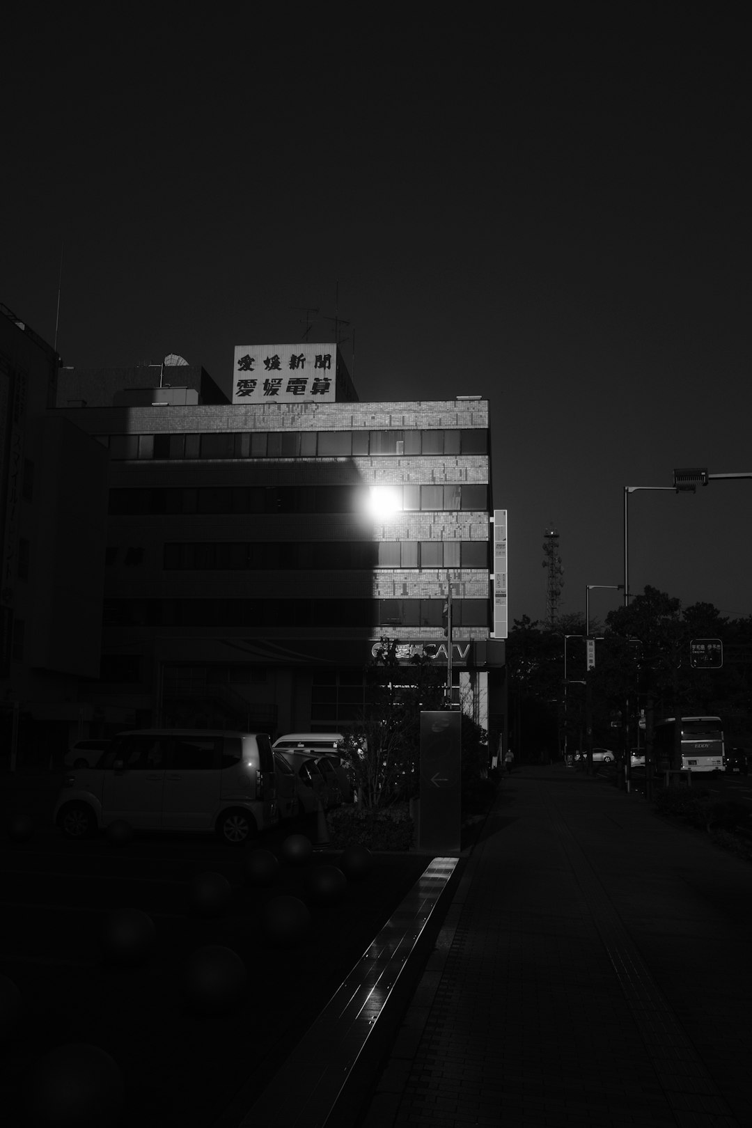 grayscale photo of cars parked near building