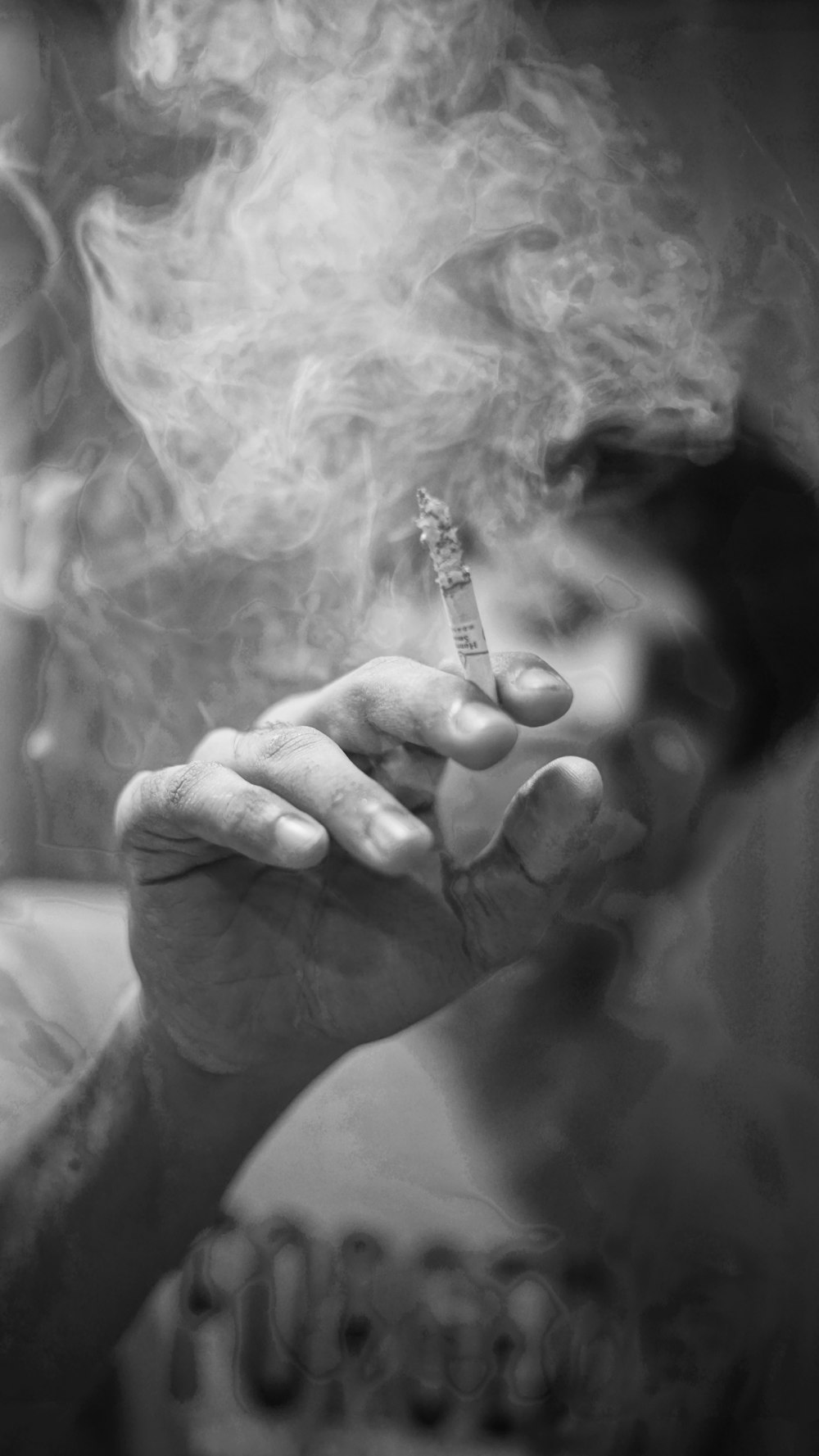 grayscale photo of person holding cigarette stick
