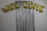 A colorful balloon garland framing a 'Welcome Baby' sign with cute baby footprints.