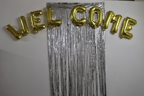 A colorful balloon garland framing a 'Welcome Baby' sign with cute baby footprints.