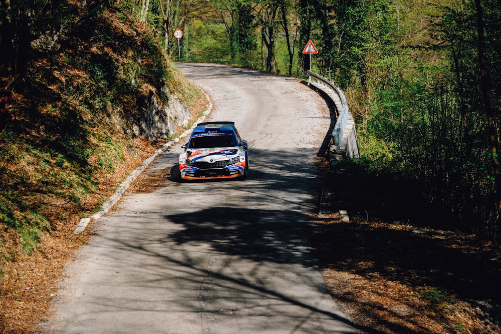 blue car on road between trees during daytime