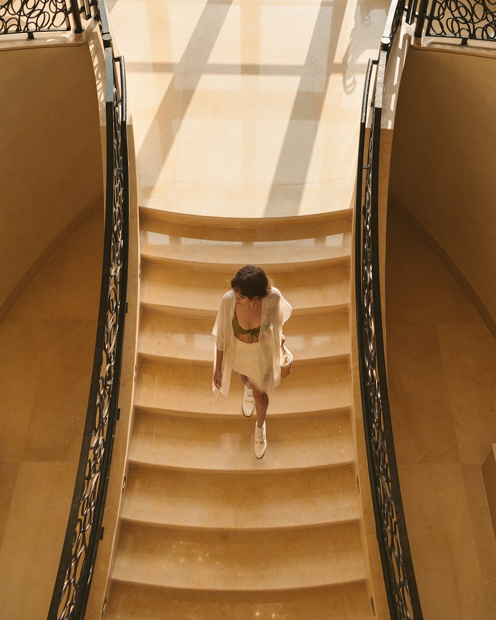 woman in white shirt and black pants walking down on white staircase
