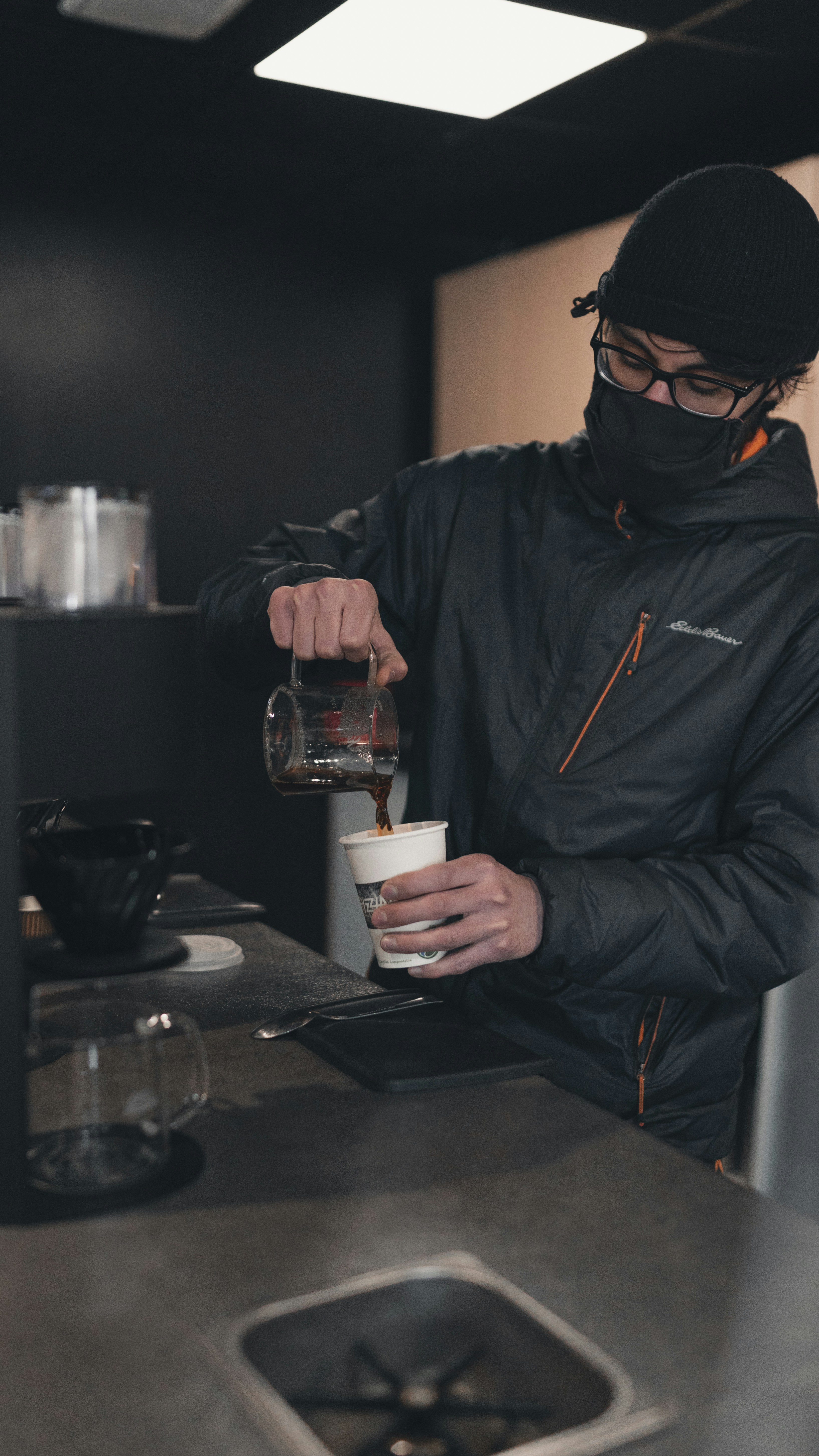 woman in black leather jacket holding clear glass mug