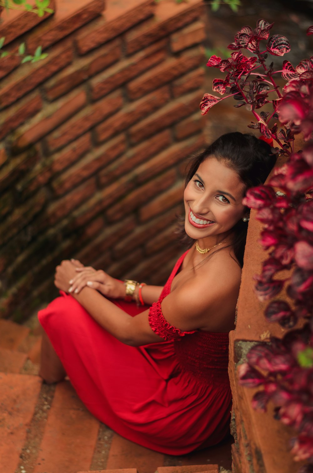 woman in red spaghetti strap dress sitting on brown concrete bench