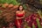 woman in red tube dress standing beside red flowers