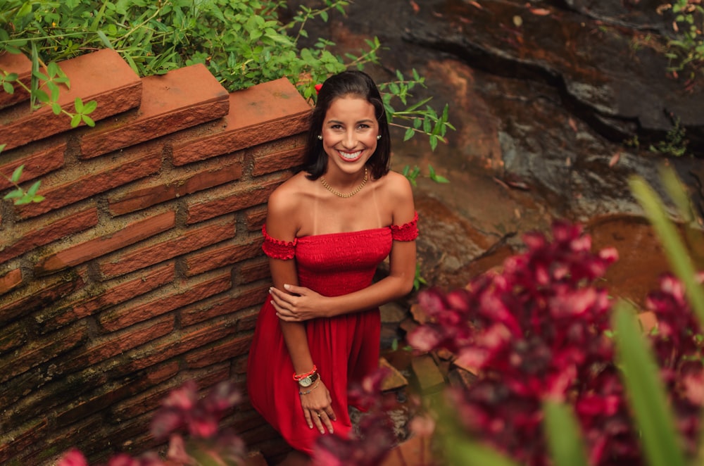 woman in red tube dress standing beside red flowers