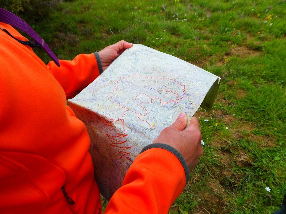 Person im orangefarbenen Langarmhemd mit weißem Druckerpapier