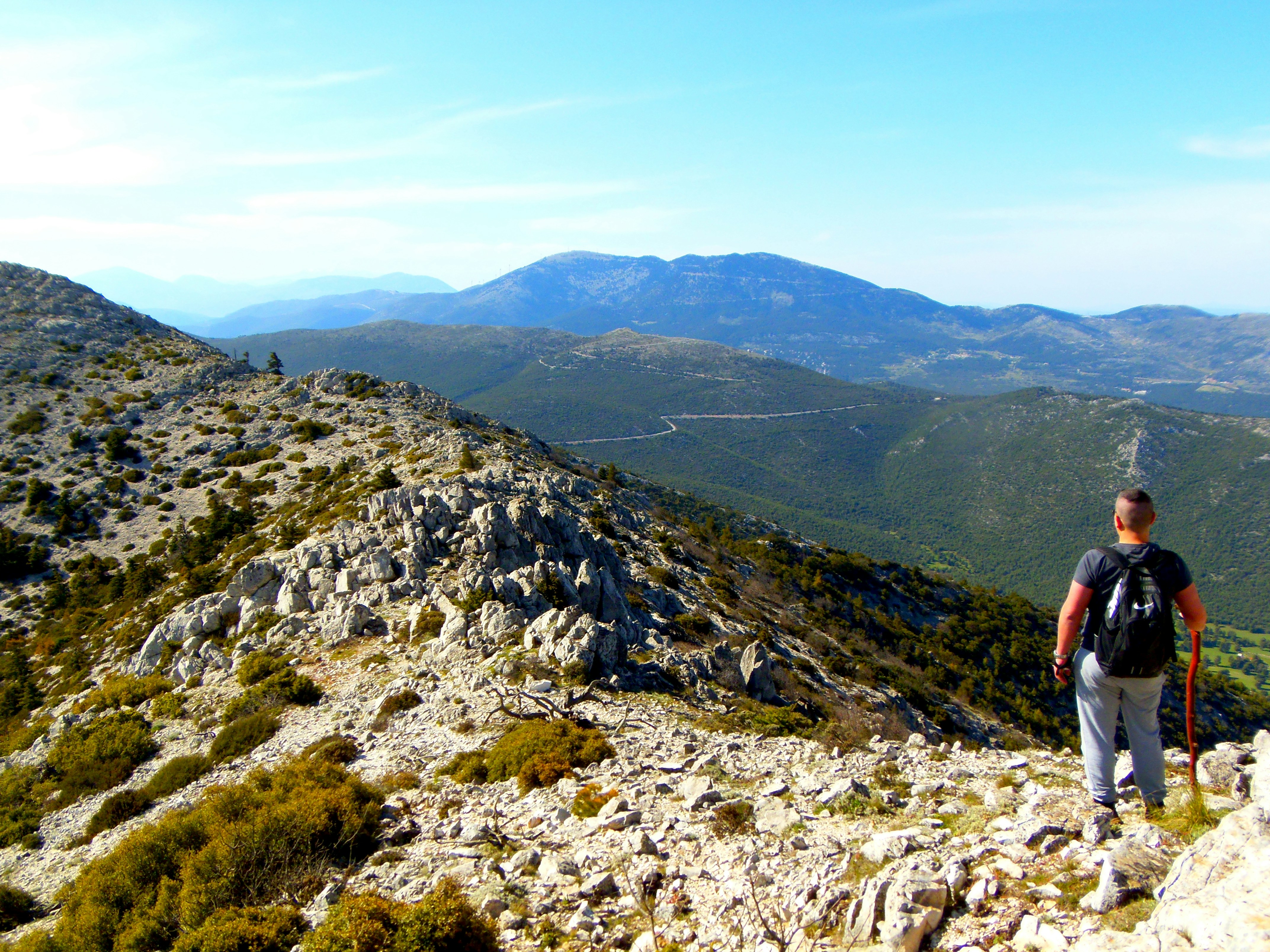 Uomo in maglietta nera e pantaloncini di jeans blu che cammina sulla montagna rocciosa durante il giorno