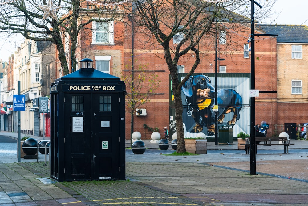 black police box on sidewalk during daytime