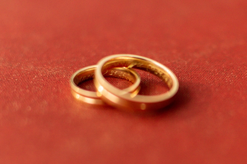 gold wedding band on red textile