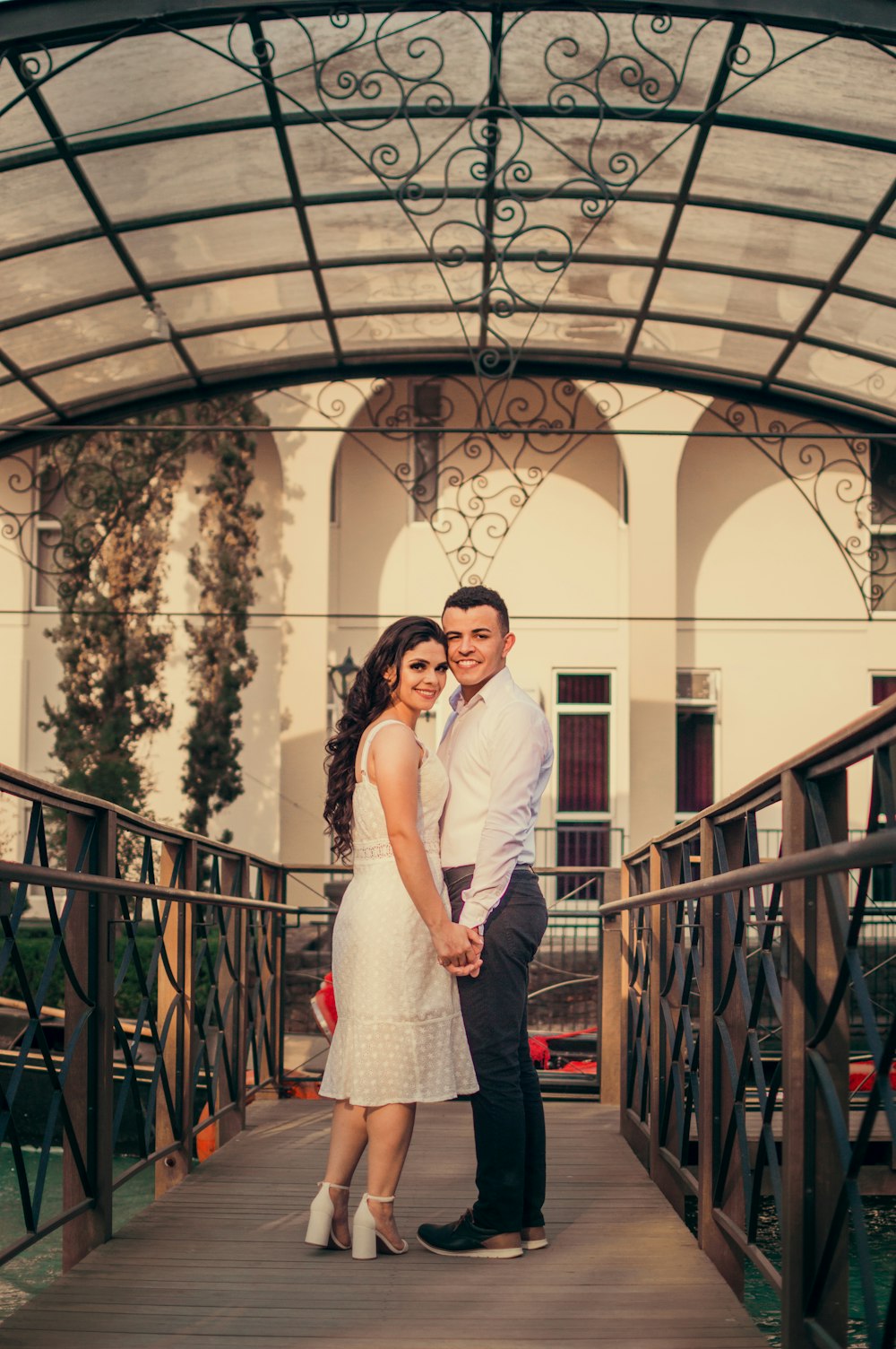 man in white dress shirt and woman in white dress standing on red metal staircase