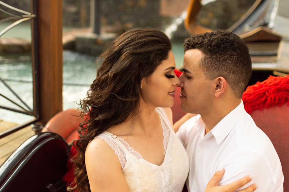 man in white suit kissing woman in white sleeveless dress