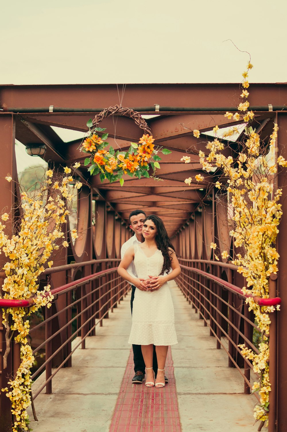 woman in white dress standing on brown wooden bridge