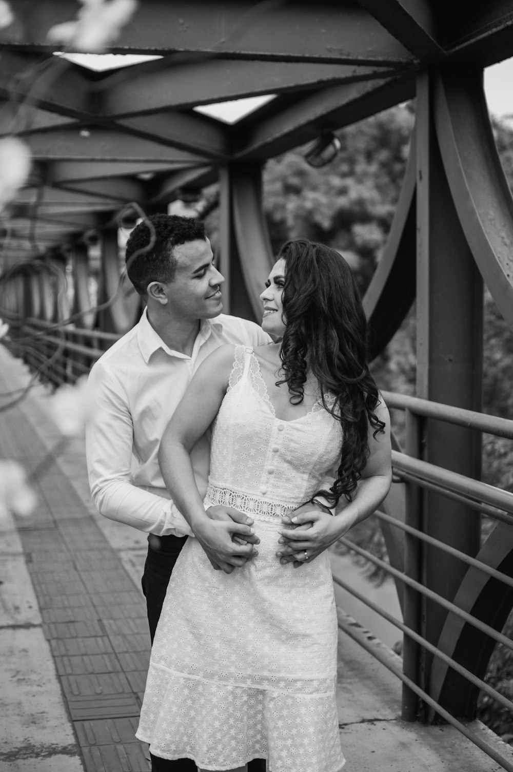 man in white dress shirt and woman in white dress standing on wooden bridge