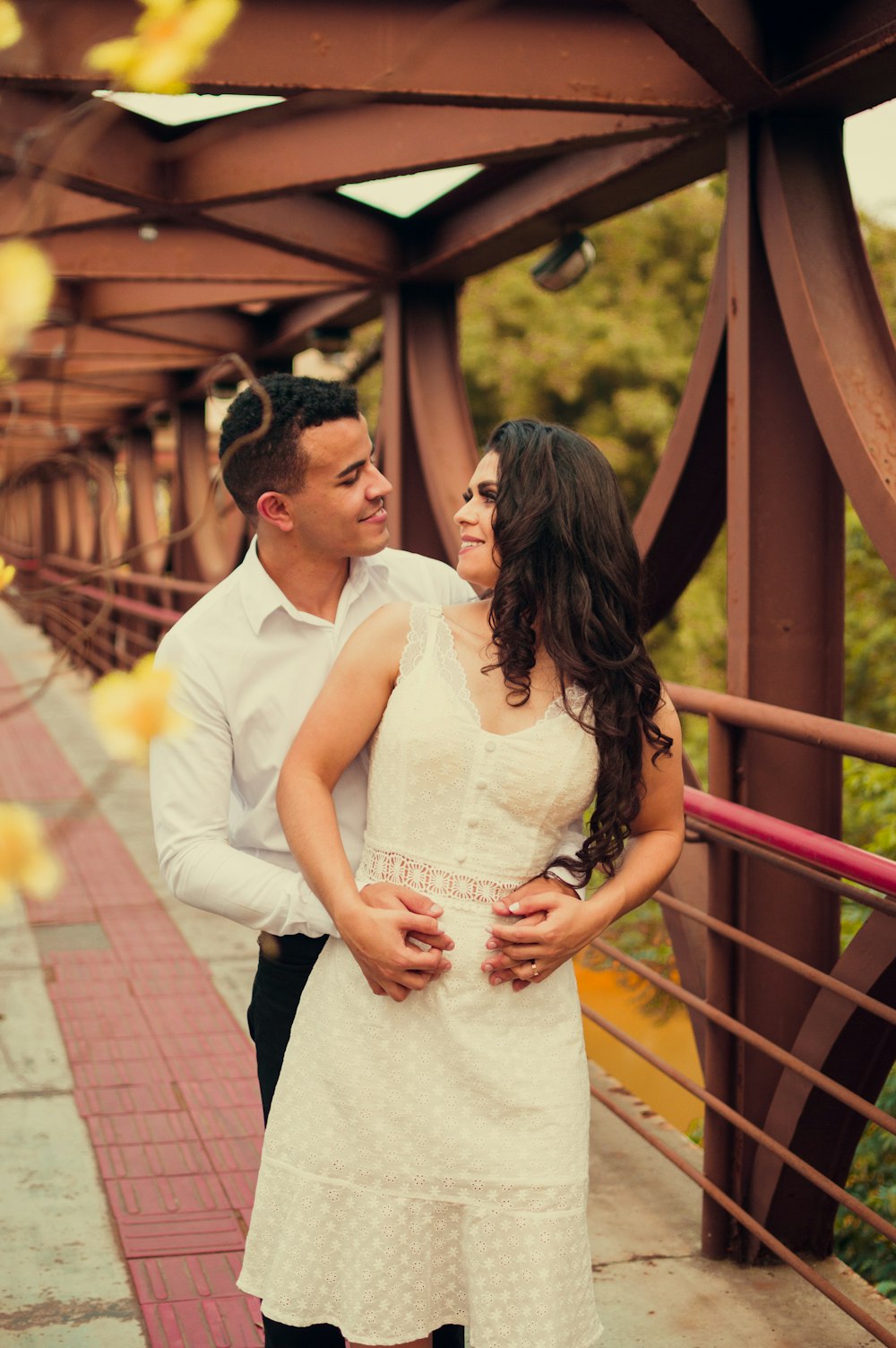 man in white dress shirt and woman in white dress standing on brown wooden bridge during