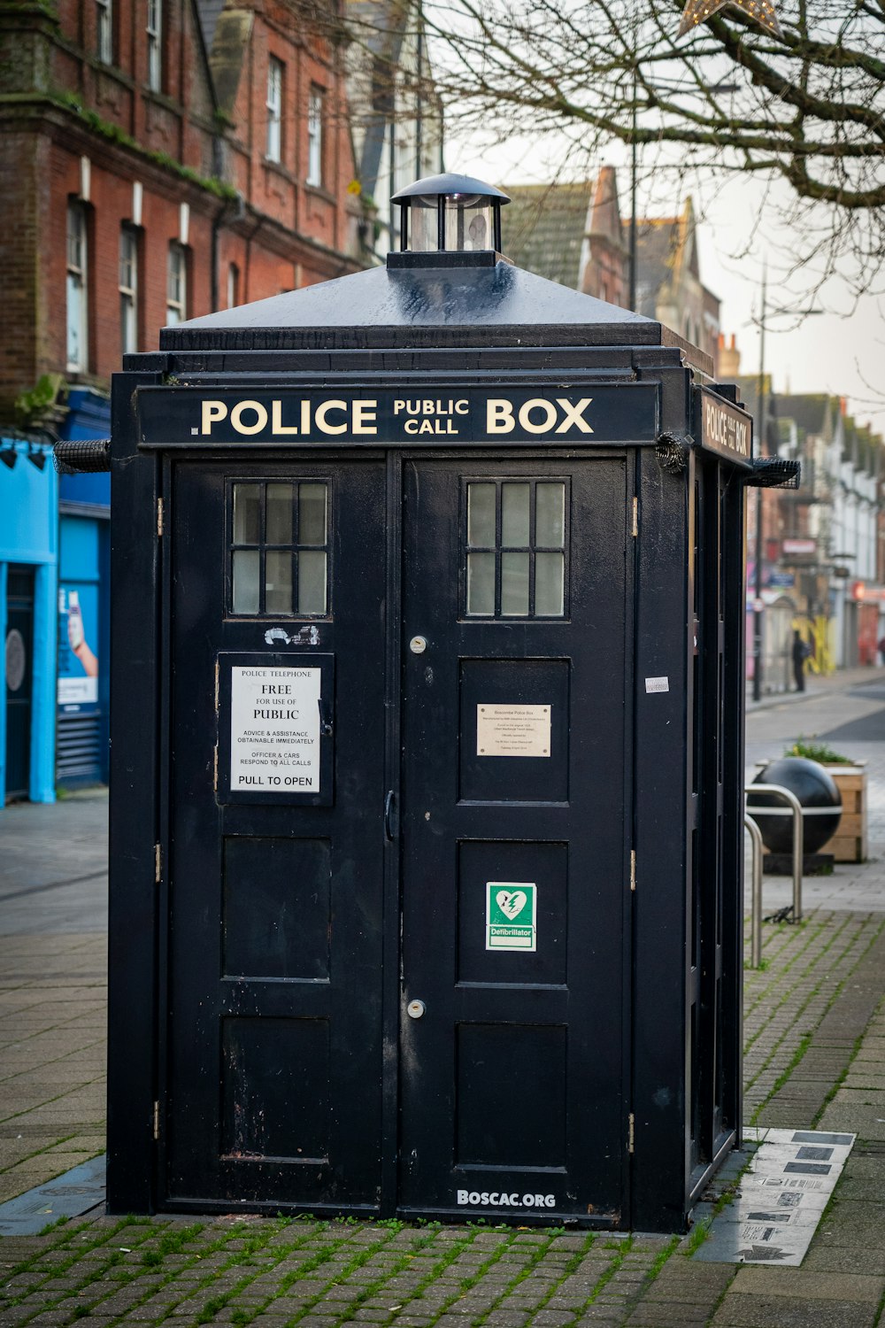 black police box on sidewalk during daytime