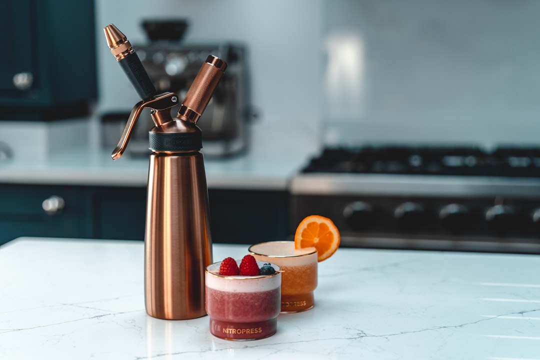 stainless steel vacuum flask beside orange plastic bottle