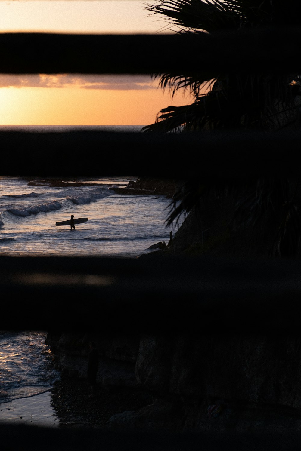 silhouette of person standing on rock formation near body of water during sunset