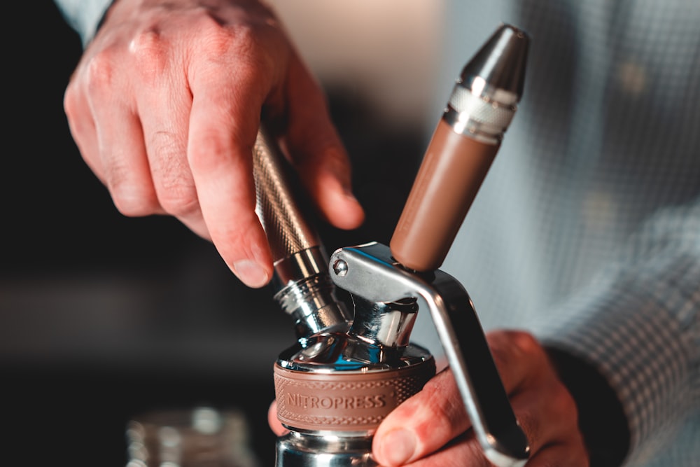 person holding brown and silver hand tool