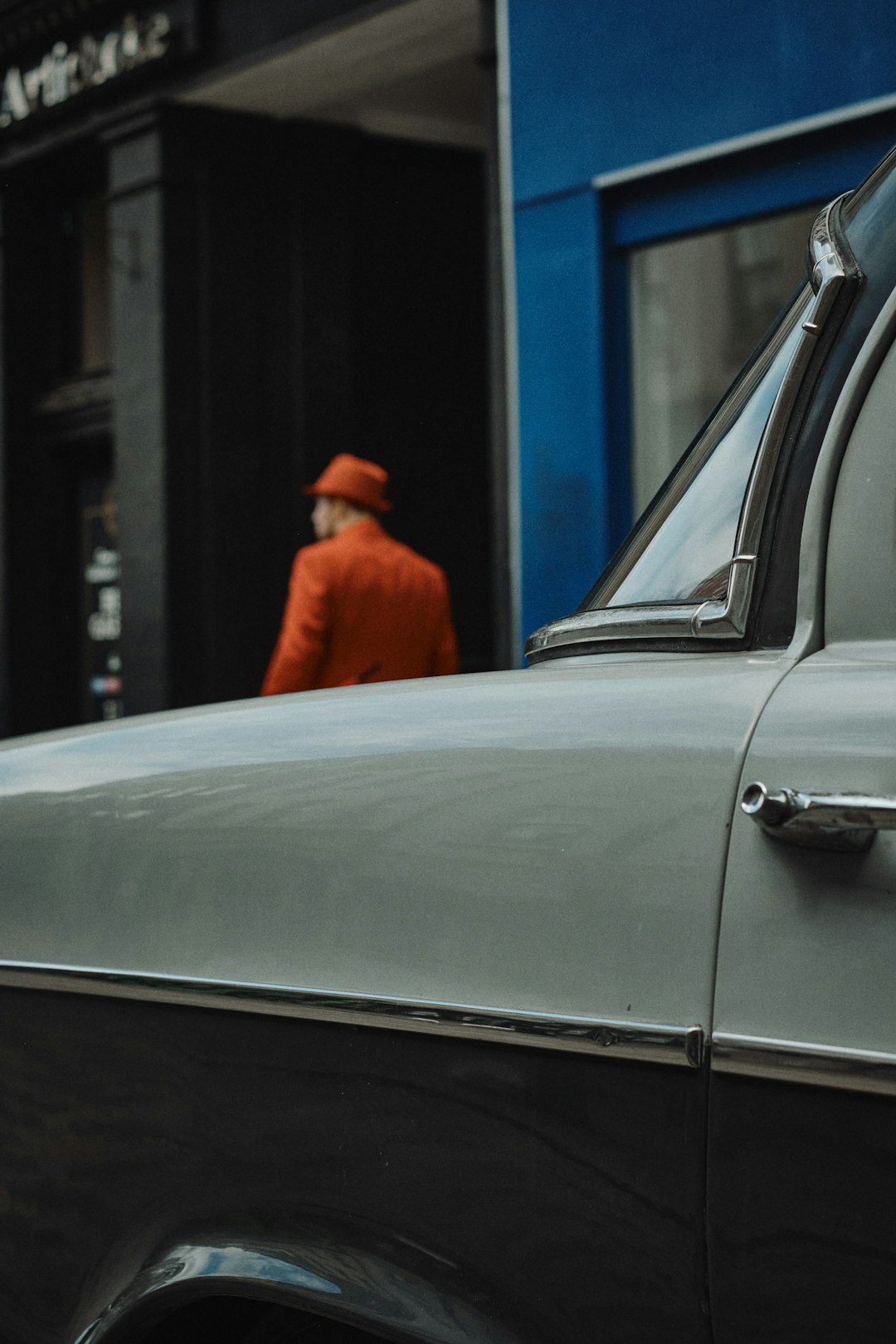 man in orange jacket standing beside white car during daytime