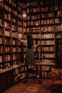 woman in black dress standing in front of books