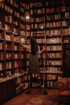 woman in black dress standing in front of books