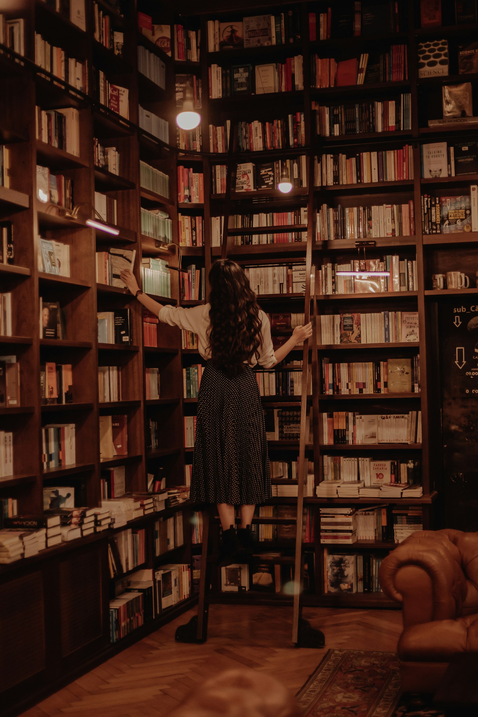 woman in black dress standing in front of books