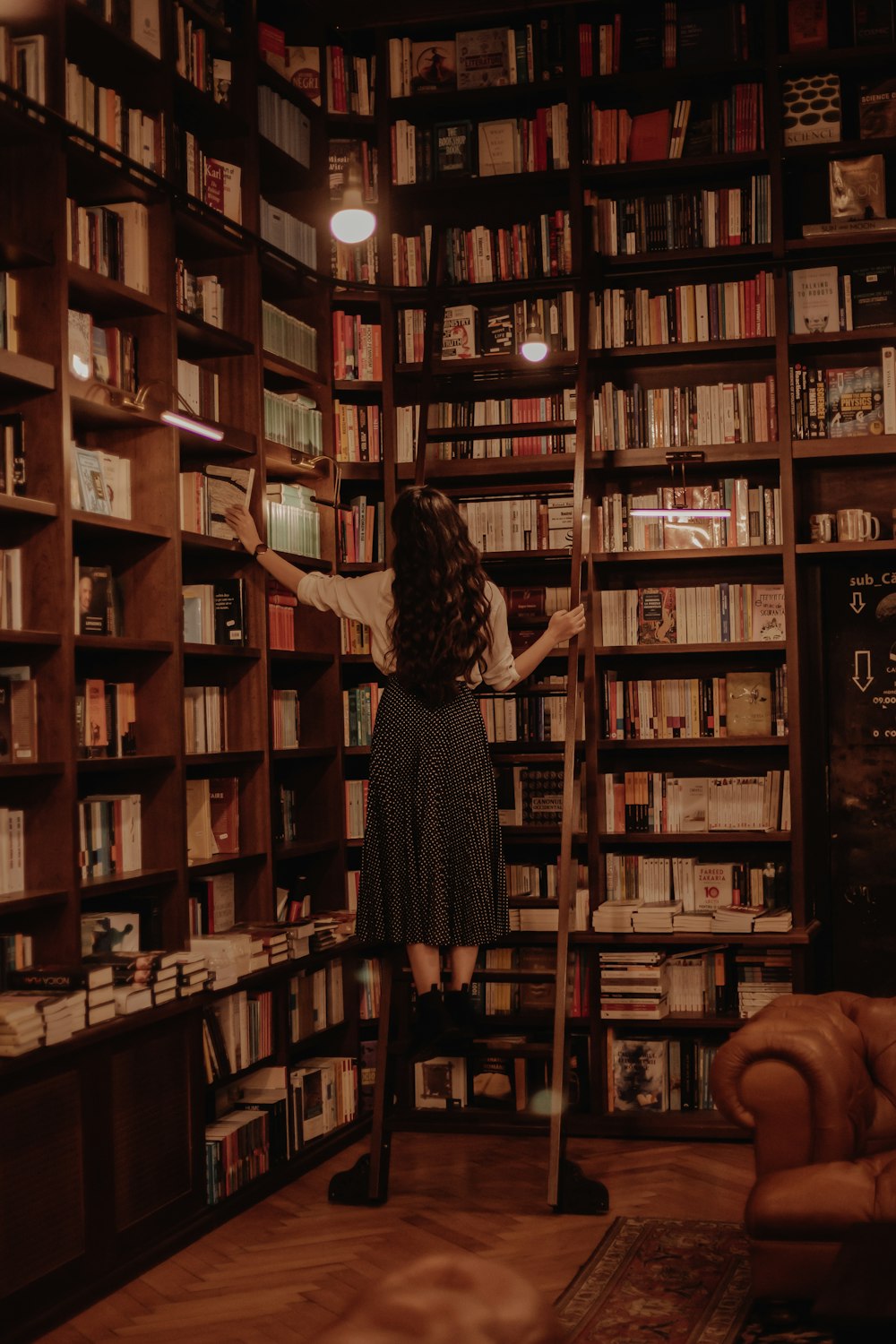 woman in black dress standing in front of books