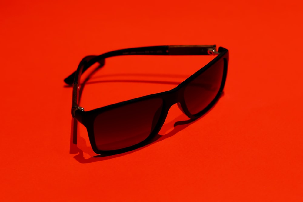 occhiali da sole con montatura nera su superficie arancione