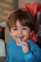 boy in blue crew neck shirt holding blue and white plastic toy