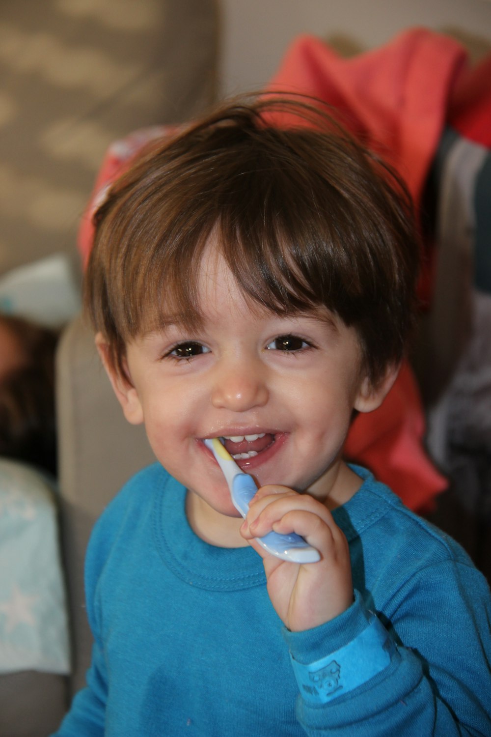 boy in blue crew neck shirt holding blue and white plastic toy