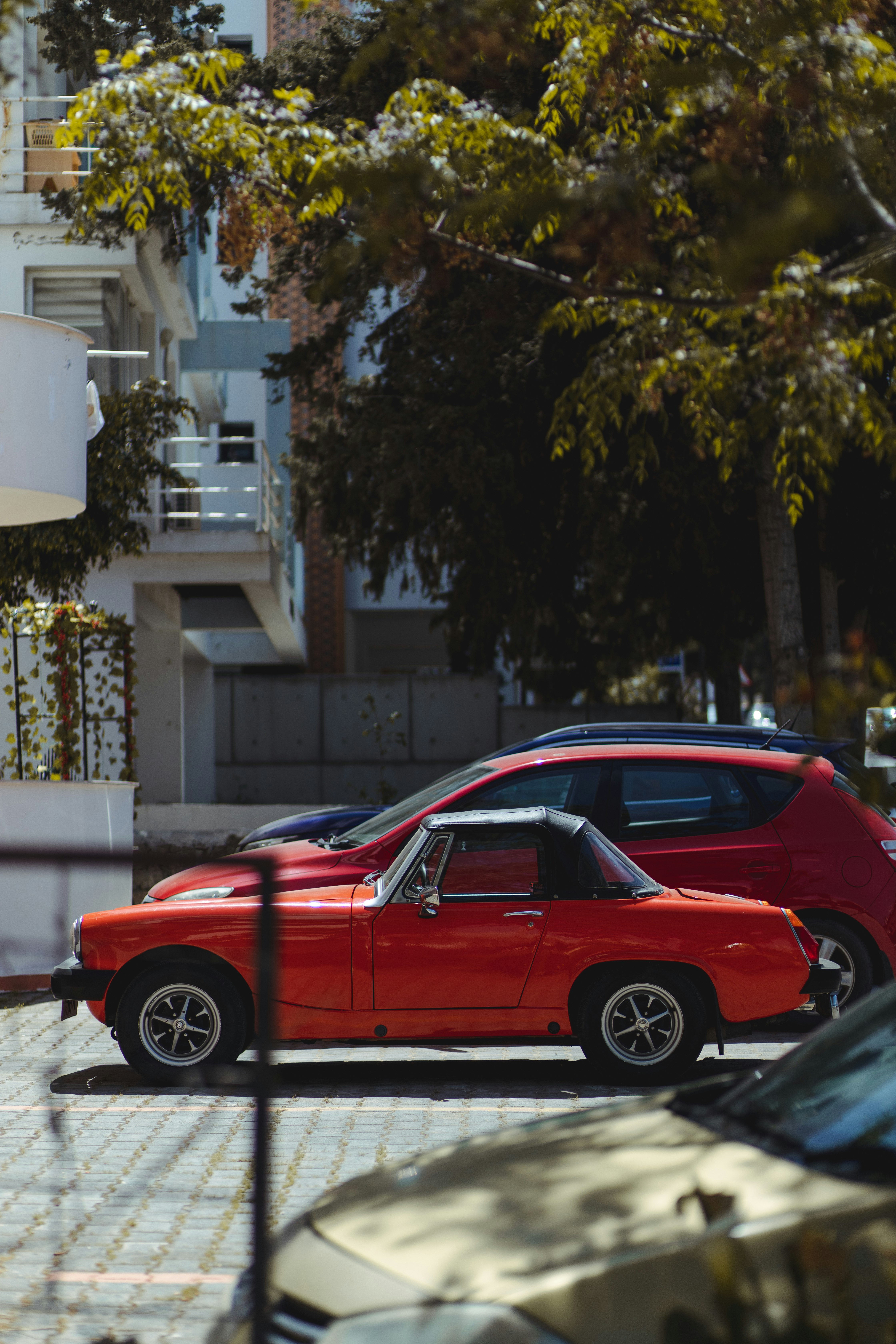 red sedan parked near white building during daytime