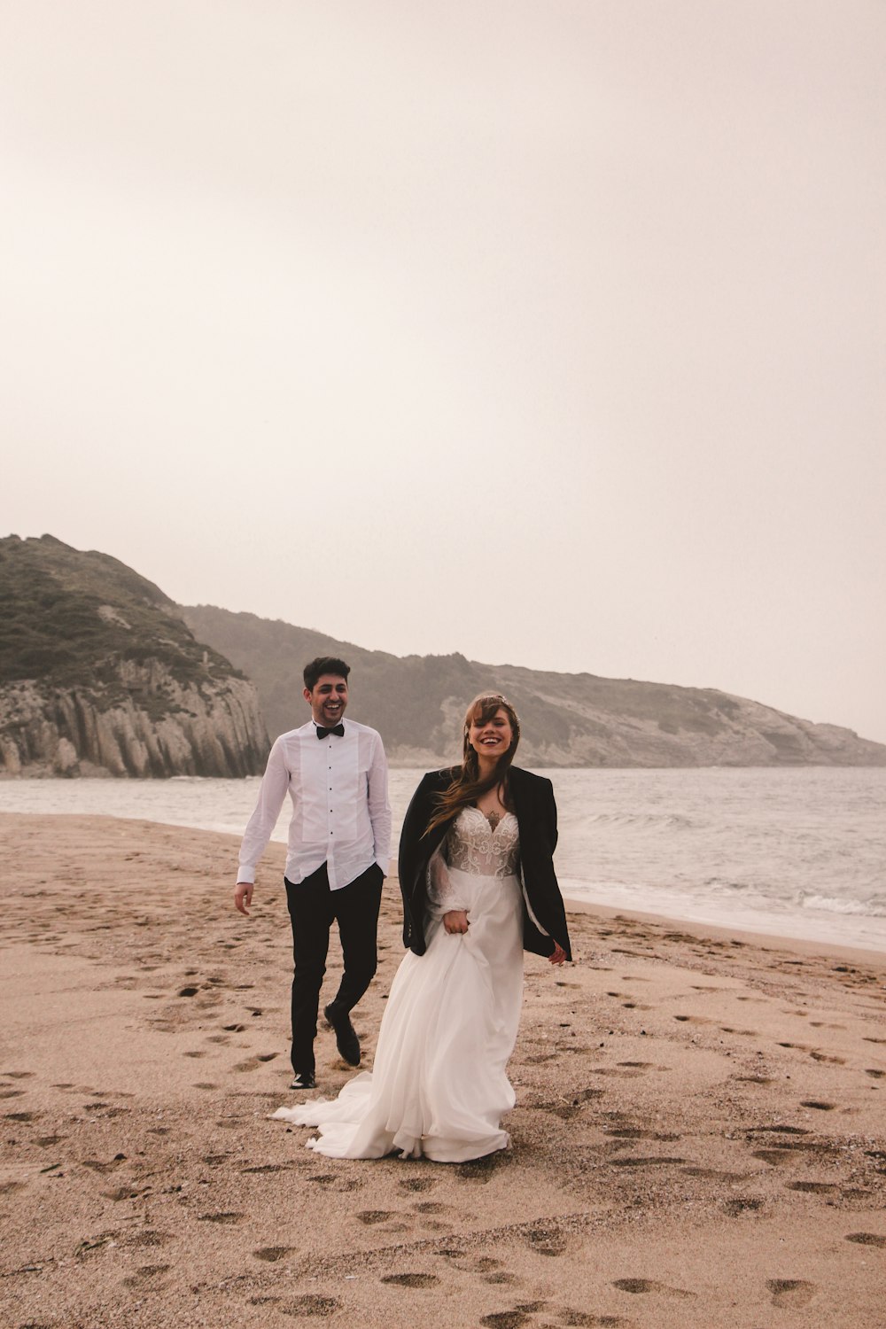 man and woman standing on beach during daytime